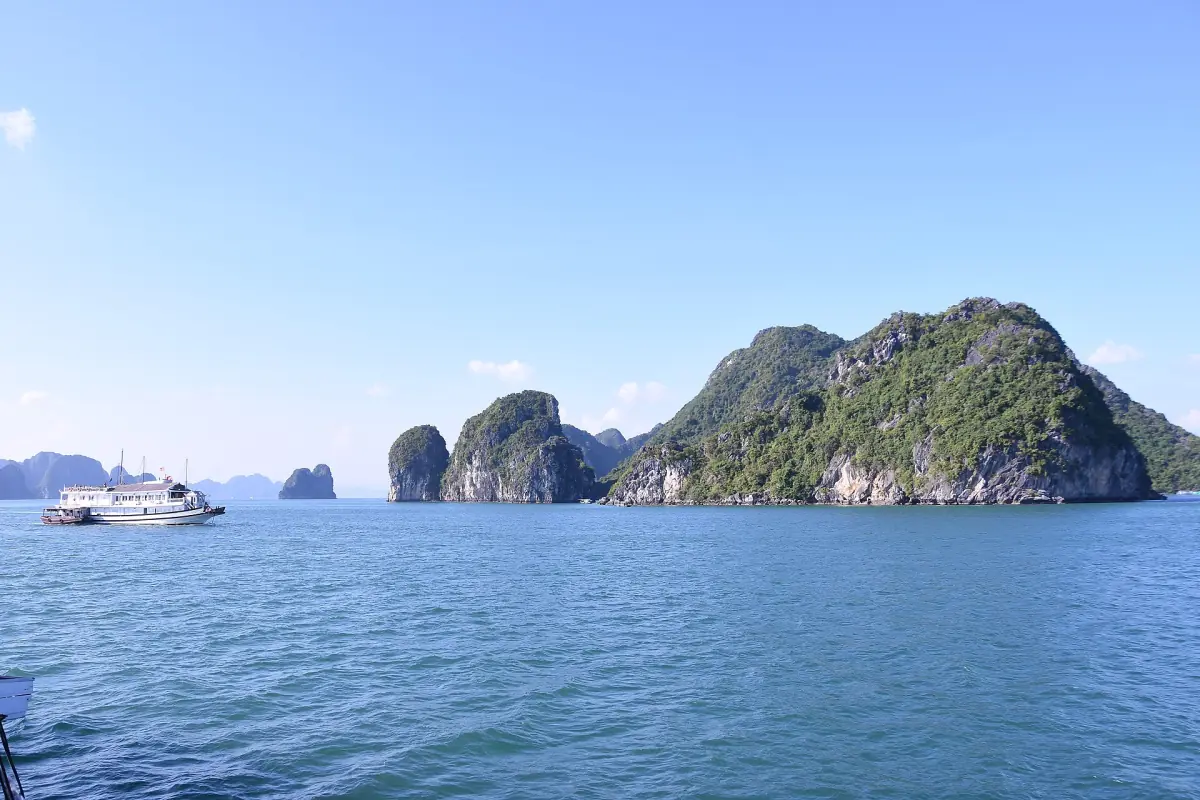 Ein Ausflugsschiff fährt an Karstinseln in der Halong-Bucht vorbei